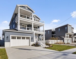 A multi-story residential building with a garage, a balcony on the second floor, and a staircase leading to the upper levels.