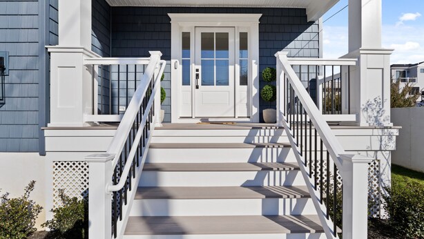 A two-story house with a white front porch, a double door, and a staircase with white railings. - 6BR Heated Pool Hot Tub Game Room Elevator (Brigantine)