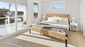 A bedroom with a large bed, a balcony, and a view of the city. - 6BR Heated Pool Hot Tub Game Room Elevator (Brigantine)