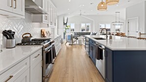 A modern kitchen with white cabinetry, a large island, and pendant lighting. - 6BR Heated Pool Hot Tub Game Room Elevator (Brigantine)