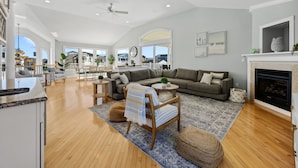 A spacious living room with a large sofa, a fireplace, and a view of the outdoors. - Heated Pool Hot Tub 5BR Game Room Elevator Cabana (Brigantine)