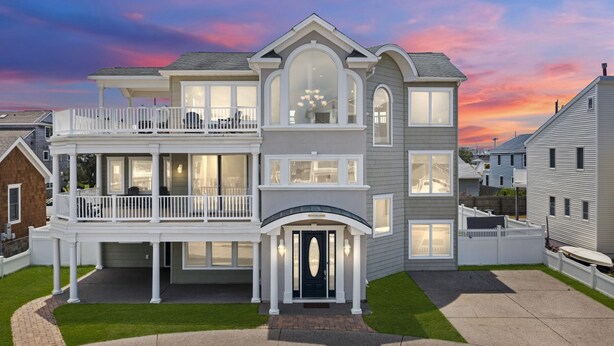 A two-story house with a balcony, a covered front porch, and a driveway. - Heated Pool Hot Tub 5BR Game Room Elevator Cabana (Brigantine)