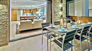 A modern dining area with a stone accent wall, a bar, and a view into the kitchen.