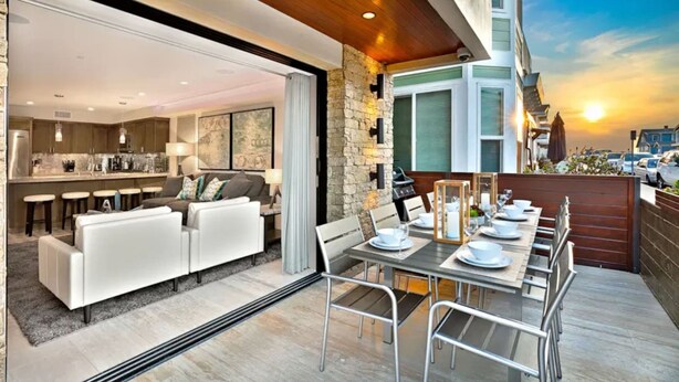 A modern kitchen with a bar area, a dining area with a table set for four, and a view of the sunset.