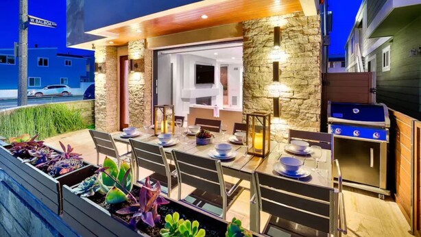 An outdoor dining area with stone walls, a grill, and a view of a street. - 7 Br 2 Hot Tubs Rooftop Beach Block Ocean View (Newport Beach)