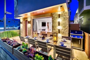 An outdoor dining area with stone walls, a grill, and a view of a street.