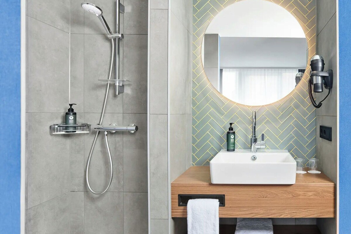 Un baño moderno con ducha, lavamanos y espejo.