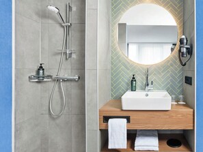 Un bagno moderno con doccia, lavandino e specchio.
