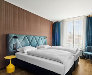 Une chambre d’hôtel avec un grand lit, une petite table et une vue sur la ville par la fenêtre.