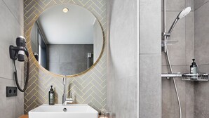 A modern bathroom with a large mirror, a rectangular sink, and a handheld showerhead.