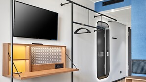 A modern room with a mounted TV, a wooden shelf with a patterned back, a blue bench, and a door with a black frame.