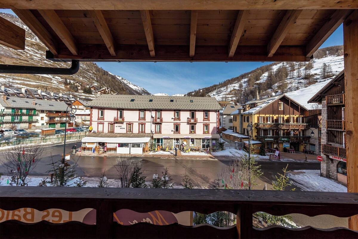 A hotel with a central courtyard, multiple balconies, and a view of snow-covered mountains.