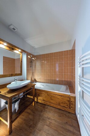 A modern bathroom with a wooden vanity, a large mirror, a bathtub, and a shower. - Madame Vacances Les Balcons du Viso (Abriès-Ristolas)