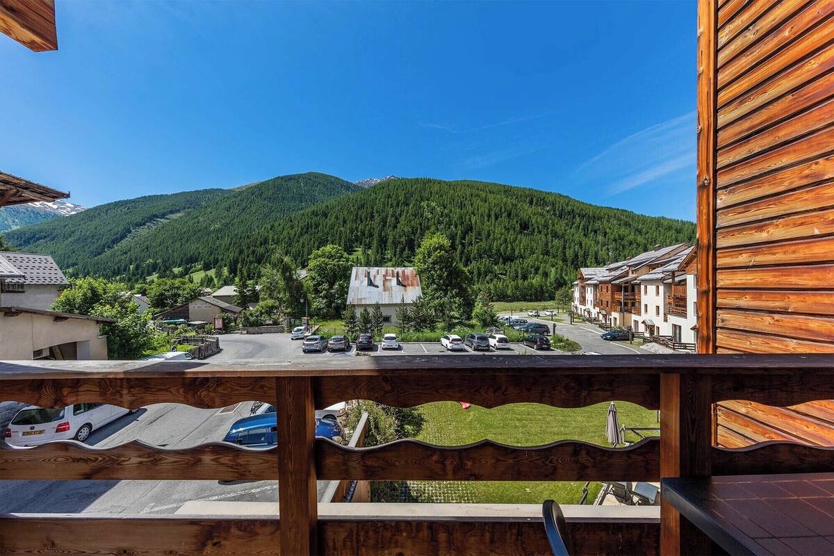 A wooden balcony overlooking a mountain village with traditional buildings and a clear sky.