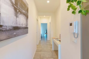 A hallway with a painting on the left, a desk with papers on the right, and a plant hanging from the ceiling. - L'Attico Dell'Edera (Bologna)