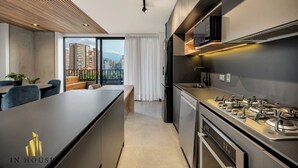 Cuina moderna amb fogó a gas, forn de microones integrat i gran finestra amb vista a la ciutat.