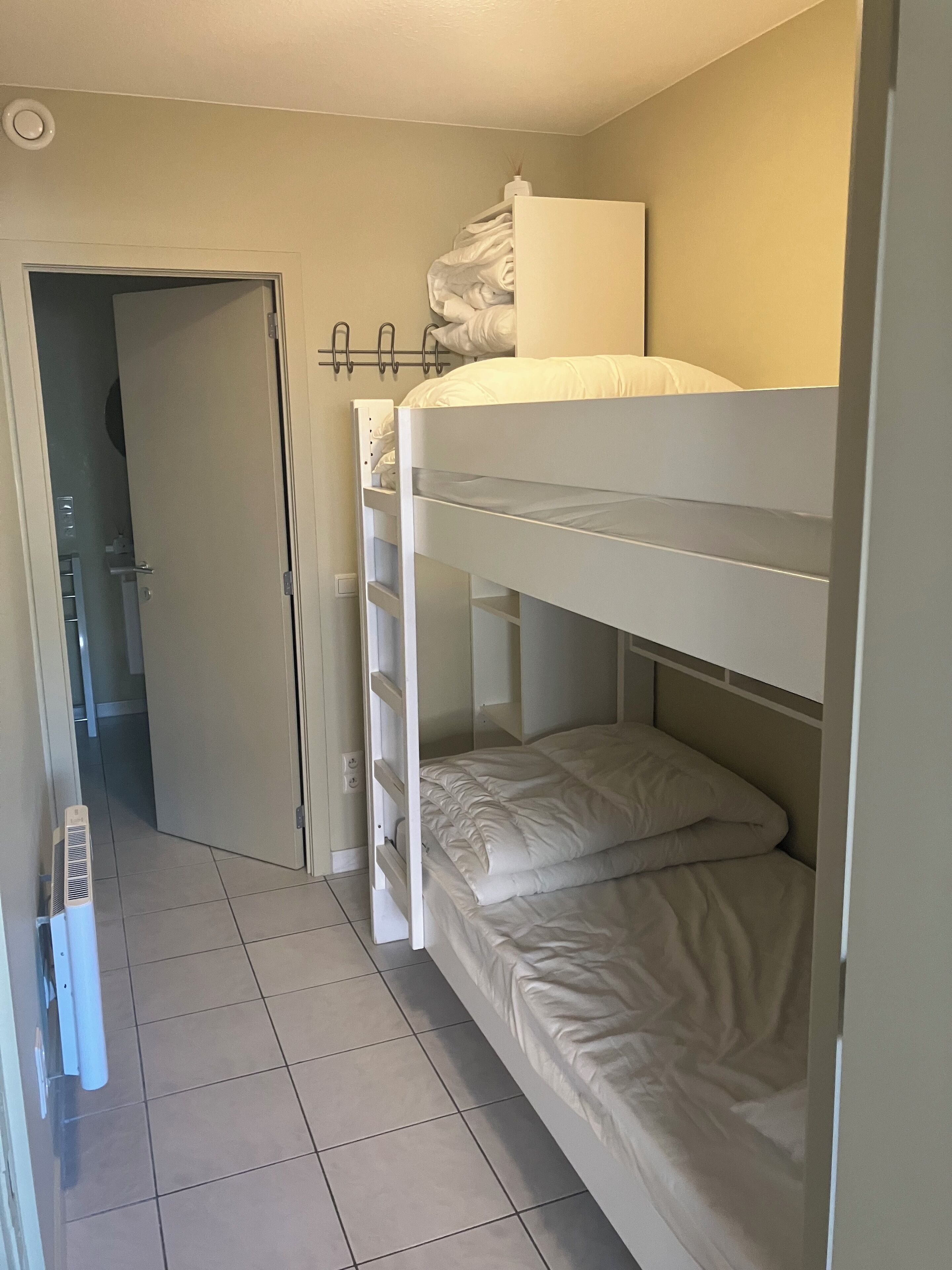 Une chambre avec des lits superposés et une porte donnant sur une salle de bain.