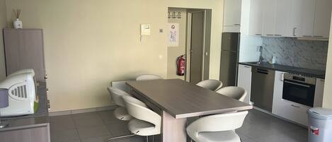 Una cocina moderna con comedor, que incluye una mesa, sillas, un refrigerador y un lavavajillas.