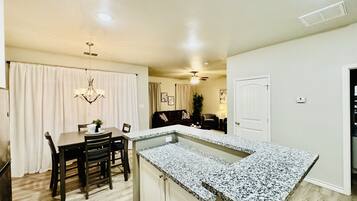 A modern kitchen with a granite countertop, wooden dining table, and chairs.