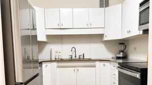 Una cocina moderna con gabinetes blancos, electrodomésticos de acero inoxidable y suelo de madera.