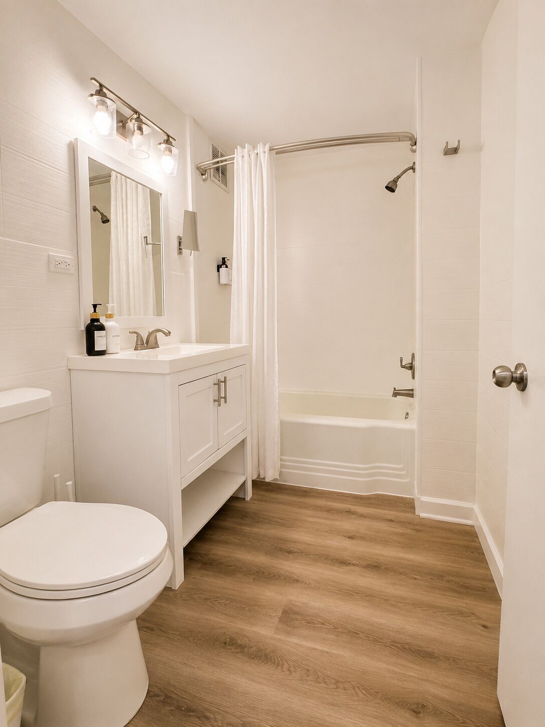 A bathroom with a toilet, vanity, mirror, shower, and bathtub.