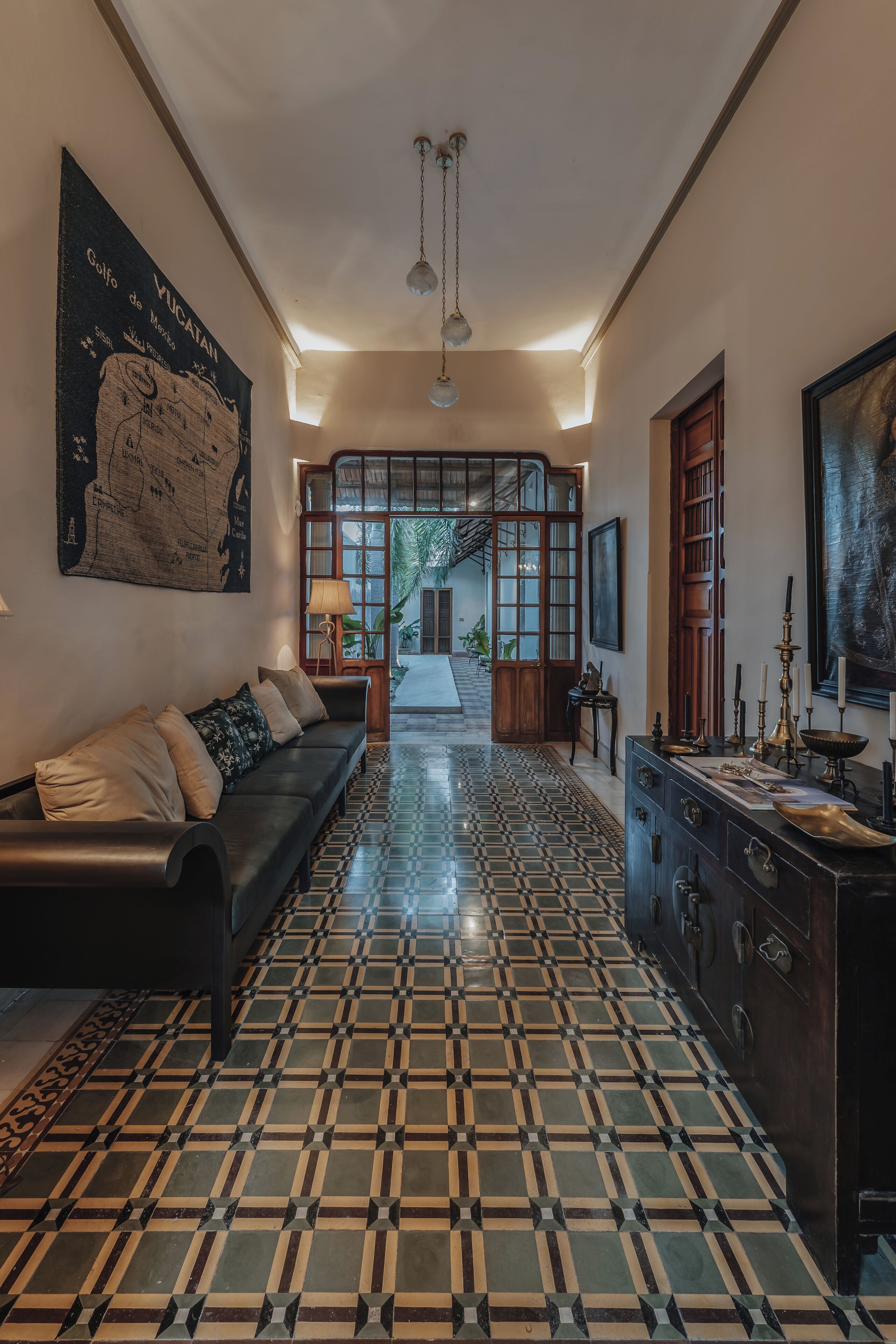 A hallway with a patterned floor, a sofa, a cabinet, and a map on the wall.