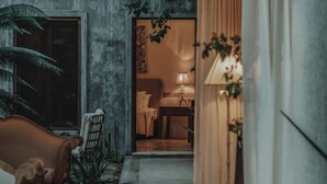 A cozy living area with a sofa, a coffee table, and a lamp. There is a doorway leading to another room with a bed and a lamp. - Casa Exclusiva Los Amigos, 4BDR by Cercana (Mérida)