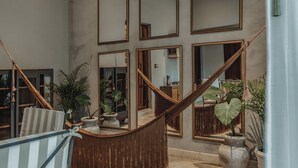 A spacious room with a large mirror wall, a hammock, and several potted plants. - Casa Exclusiva Los Amigos, 4BDR by Cercana (Mérida)