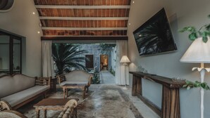 A spacious living area with a high ceiling, a large TV, and a view of the outdoors. - Casa Exclusiva Los Amigos, 4BDR by Cercana (Mérida)
