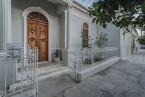 A building with a large wooden double door, a white balcony railing, and a small potted plant on the ground floor. - Casa Exclusiva Los Amigos, 4BDR by Cercana (Mérida)