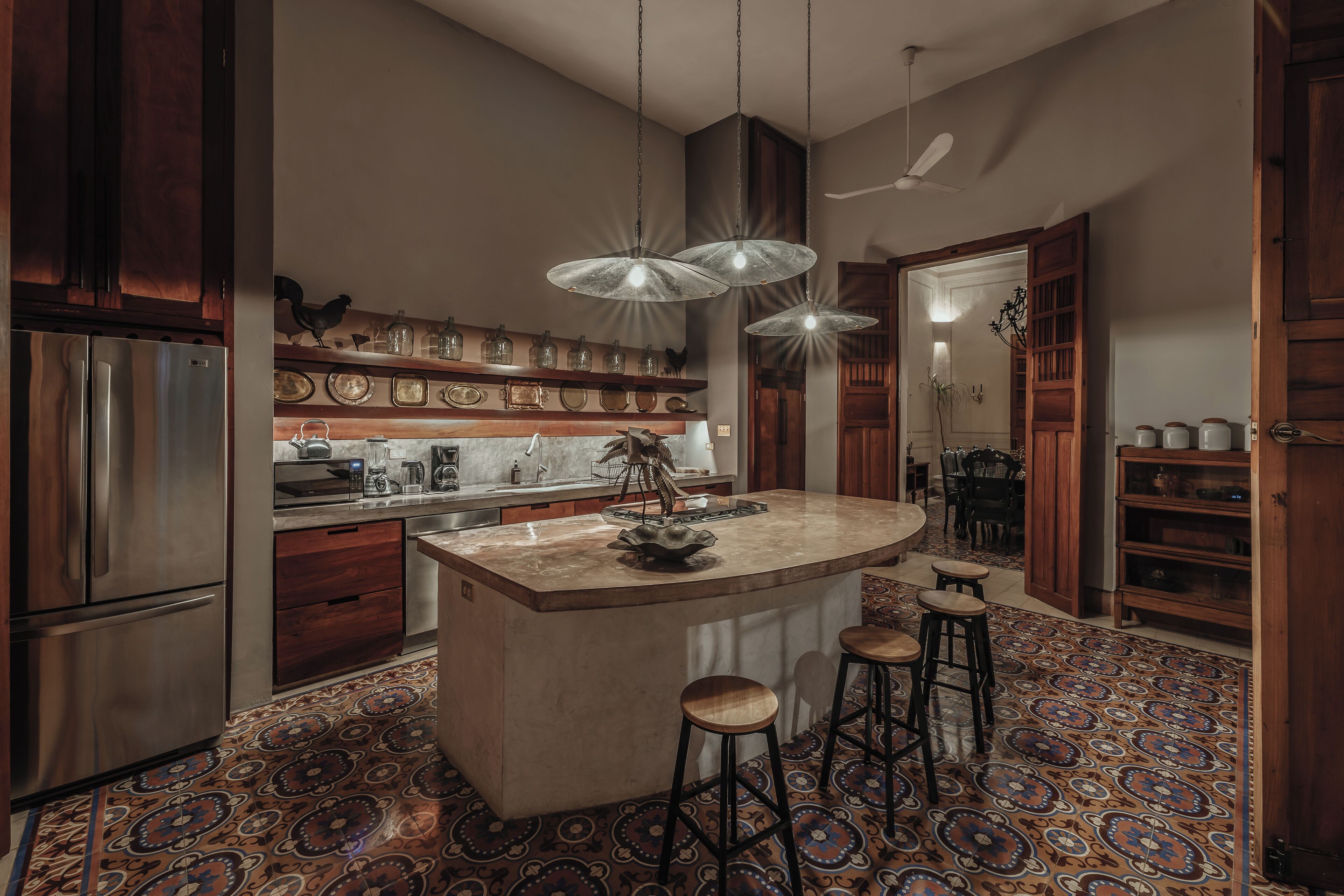A modern kitchen with a central island, bar stools, and a patterned floor.