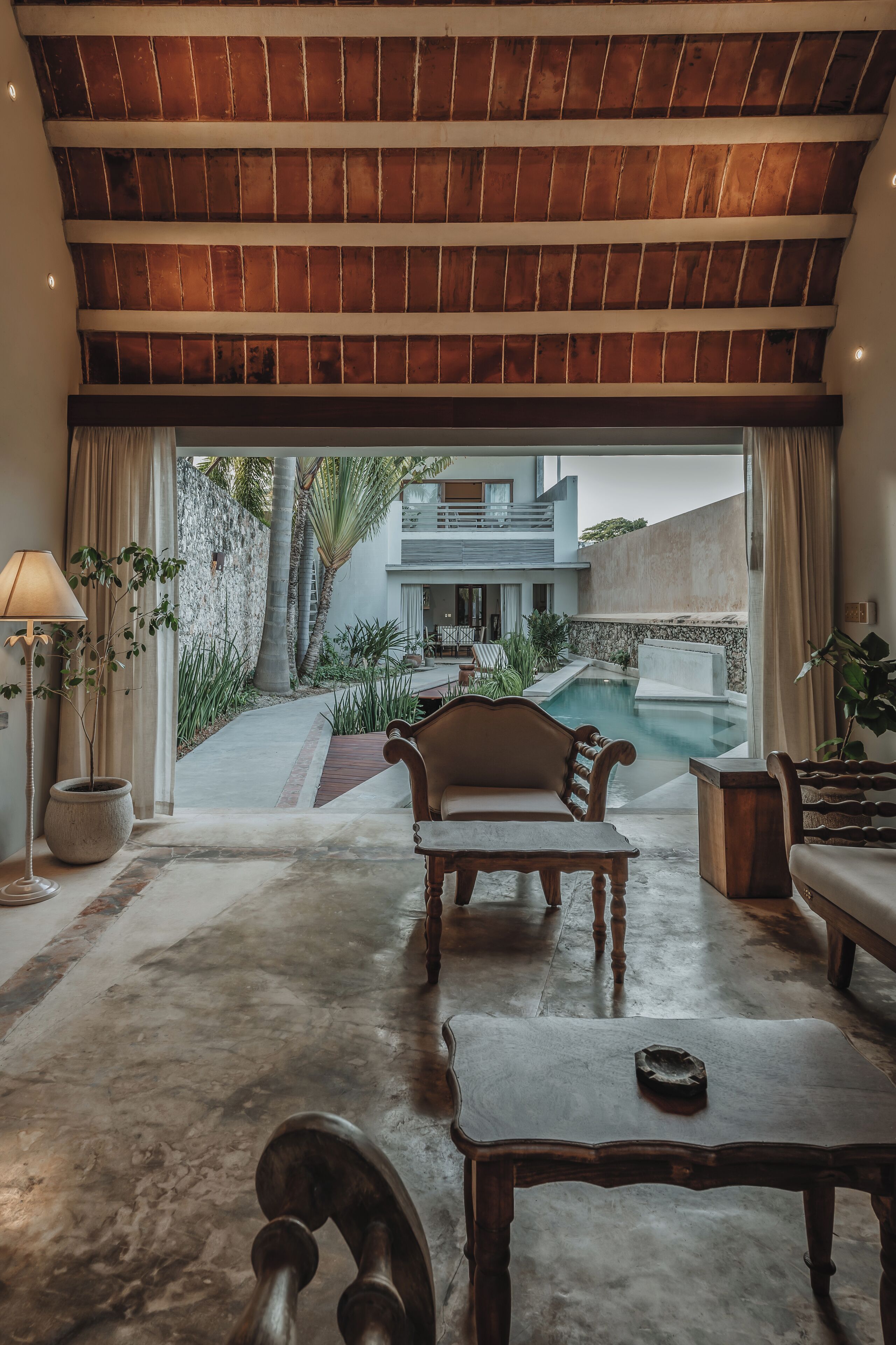 A spacious living area with a wooden ceiling, a pool, and a view of a modern building.