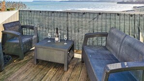En balkong med möbler i rotting, ett bord och en flaska champagne.