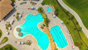An aerial view of a resort with multiple swimming pools, sun loungers, and a golf course. - Enjoy Resort living in the Upscale Lakewood National Golf Country Club community (Bradenton)