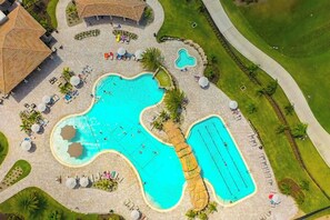 An aerial view of a resort with multiple swimming pools, sun loungers, and a golf course. - Enjoy Resort living in the Upscale Lakewood National Golf Country Club community (Bradenton)