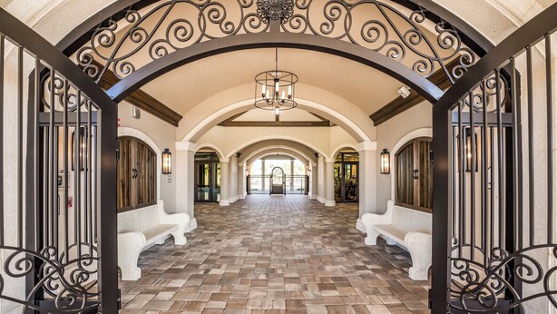 A spacious hallway with a tiled floor, white benches, and ornate black metal railings. - Enjoy Resort living in the Upscale Lakewood National Golf Country Club community (Bradenton)