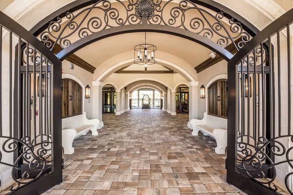 A spacious hallway with a tiled floor, white benches, and ornate black metal railings. - Enjoy Resort living in the Upscale Lakewood National Golf Country Club community (Bradenton)