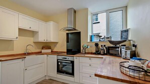 A modern kitchen with white cabinets, a built-in oven, a microwave, and a window with a view of the outside. - 2 Bed in Brixham (oc-p30465) (Brixham)