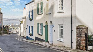 A narrow street lined with traditional buildings, featuring white walls and green shutters. - 2 Bed in Brixham (oc-p30465) (Brixham)