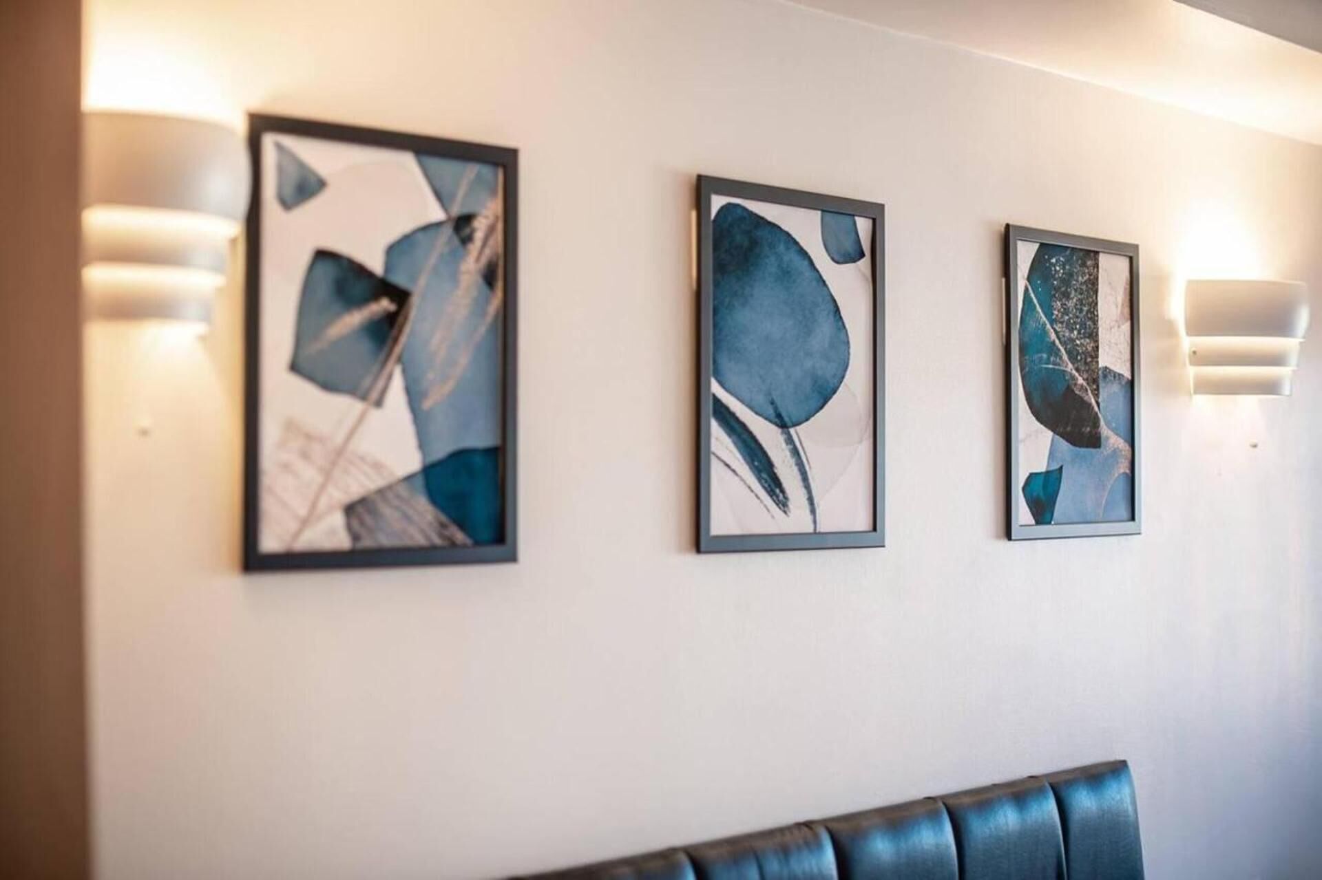 Trois tableaux abstraits sont accrochés à un mur dans le hall d’un hôtel.