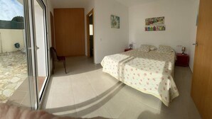 Un dormitorio con cama, mesita de noche y ventana.