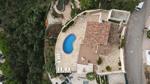 Vista aérea de una propiedad con piscina, patio cubierto y sendero de piedra.
