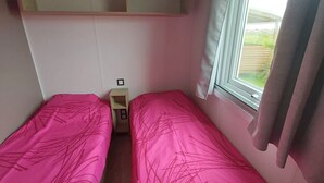 A small room with two beds, a window, and a shelf above the beds. - GOLFE DU MORBIHAN (Sarzeau)