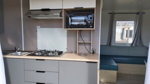 A compact kitchenette with a gas stove, microwave, and a small shelf. - GOLFE DU MORBIHAN (Sarzeau)