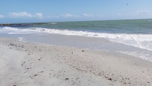 A beach with waves, a clear sky, and a distant shoreline. - GOLFE DU MORBIHAN (Sarzeau)