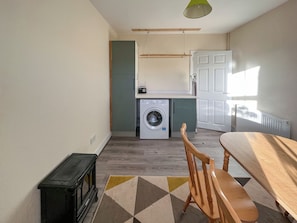 Una cocina compacta con lavadora, una mesa de comedor y una silla.