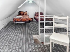 Um quarto com uma cama beliche, uma cama de solteiro e uma cadeira.