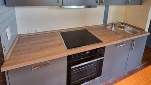 A modern kitchen with grey cabinets, a wooden countertop, a built-in stove, and a sink. - Small country house 2B in the Westerwald. Family-friendly, pet-friendly and close to nature (Welschneudorf)