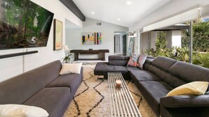 A modern living room with dark sofas, a coffee table, and artwork on the walls. - The Colony Enclave - #1 Hideaway in Palm Springs (Palm Springs)