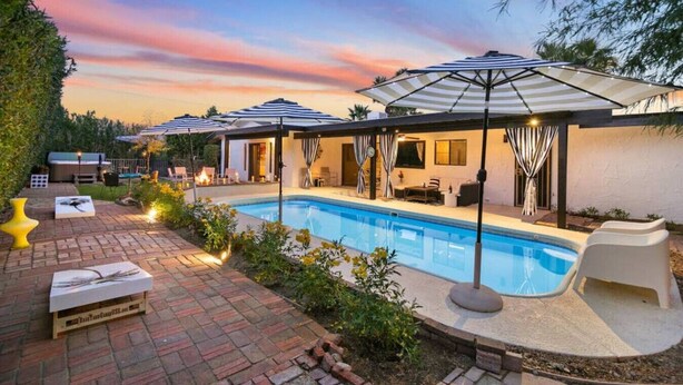 A backyard with a swimming pool, outdoor seating, and umbrellas. - The Colony Enclave - #1 Hideaway in Palm Springs (Palm Springs)